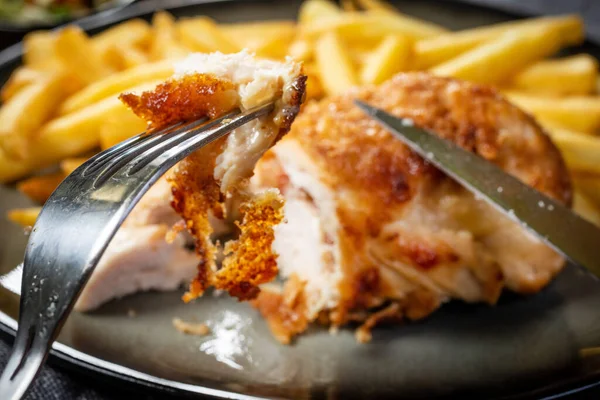 Pastırma ve peynirle doldurulmuş kızarmış tavuk göğsü patates kızartması ve salata ile servis edilir. Küçük alan derinliği.