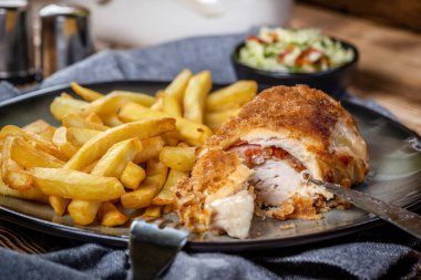 Pastırma ve peynirle doldurulmuş kızarmış tavuk göğsü patates kızartması ve salata ile servis edilir. Küçük alan derinliği.