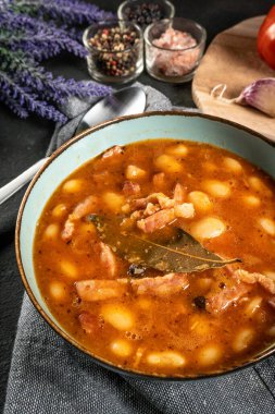 Domates soslu fasulye, pastırma ve siyah kasede sosis. Seçici odak.