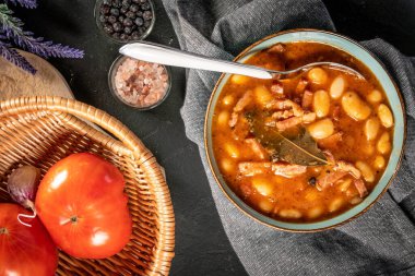 Domates soslu fasulye, pastırma ve siyah kasede sosis. Seçici odak.