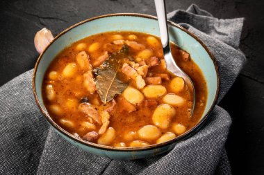 Domates soslu fasulye, pastırma ve siyah kasede sosis. Seçici odak.