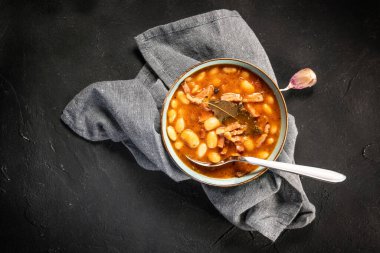 Domates soslu fasulye, pastırma ve siyah kasede sosis. Seçici odak.