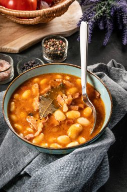 Domates soslu fasulye, pastırma ve siyah kasede sosis. Seçici odak.