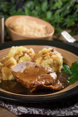 Kendi sosunda haşlanmış patates ve kızarmış lahanayla servis edilen haşlanmış domuz boynu. Sığ alan derinliği.