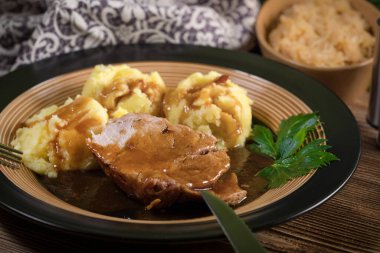 Kendi sosunda haşlanmış patates ve kızarmış lahanayla servis edilen haşlanmış domuz boynu. Sığ alan derinliği.