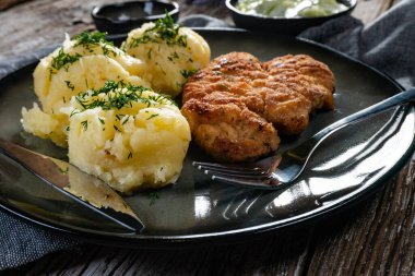 Domuz pirzolası, patates püresi ve salatalık salatasıyla servis edilir..