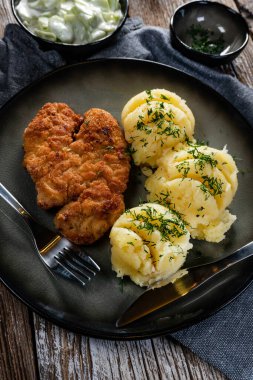 Domuz pirzolası, patates püresi ve salatalık salatasıyla servis edilir..