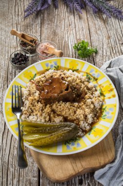 Et suyuna bulanmış domuz budu ve ahşap masada arpa..