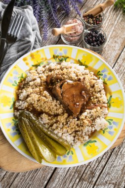 Et suyuna bulanmış domuz budu ve ahşap masada arpa..