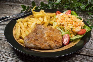 Geleneksel Polonya yemeği: kızarmış domuz pirzolası, patates kızartması ve salata ile servis edilir.. 