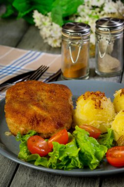 Pirzola, domuz jambonlu, haşlanmış patates ve tabakta salata..