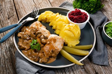 Mantar soslu ızgara tavuk göğsü, patates püresi ve salatalık turşusu ile servis edilir..