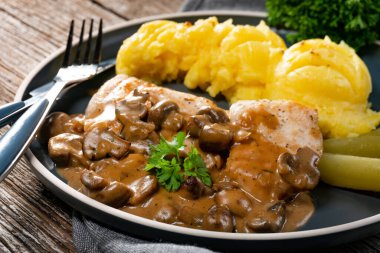 Mantar soslu ızgara tavuk göğsü, patates püresi ve salatalık turşusu ile servis edilir..