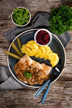 Mantar soslu ızgara tavuk göğsü, patates püresi ve salatalık turşusu ile servis edilir..