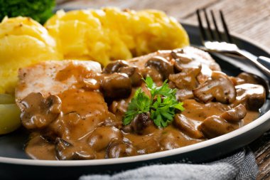 Mantar soslu ızgara tavuk göğsü, patates püresi ve salatalık turşusu ile servis edilir..