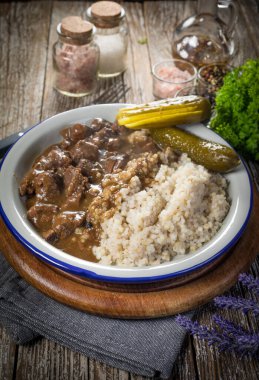 Arpa ve salatalık turşusuyla servis edilen sığır eti güveci. Seçici odak.