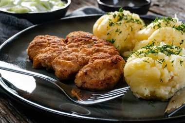 Domuz pirzolası, patates püresi ve salatalık salatasıyla servis edilir..