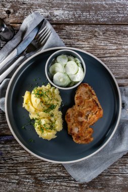 Domuz pirzolası, patates püresi ve salatalık salatasıyla servis edilir..
