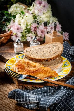 Ekmek dilimleriyle servis edilen kızarmış morina filetosu. Sığ alan derinliği.