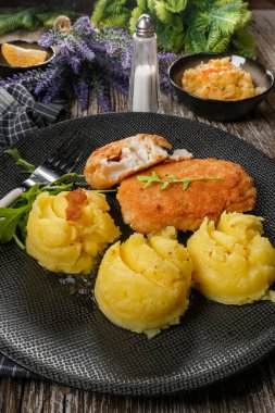 Haşlanmış patates ve sebze salatasıyla servis edilen kızarmış morina filetosu..