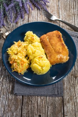 Haşlanmış patates ve sebze salatasıyla servis edilen kızarmış morina filetosu..