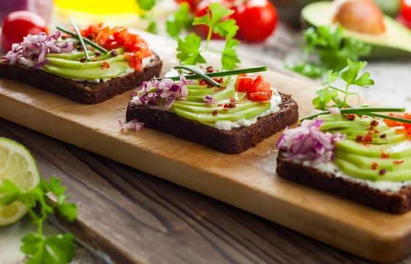 Čerstvé Vegetariánské Sendviče Černý Chléb Avokádem Rajčaty Červenou Cibulí Dřevěné — Stock fotografie