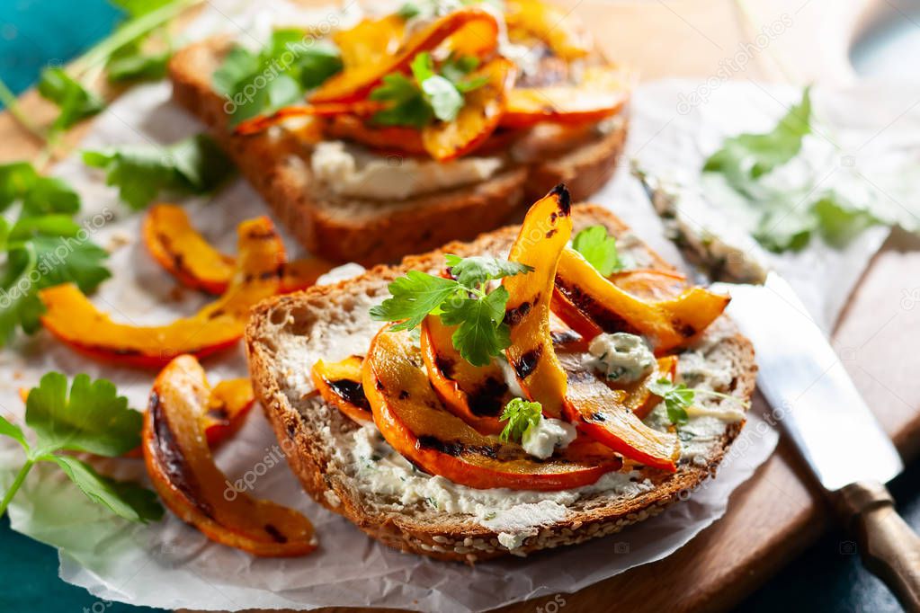 Open sandwich with grilled pumpkin and soft cheese  on multigrain rye bread.