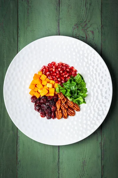 Autumn-winter season salad with roasted pumpkin, dried cranberry, pecan and pomegranate seeds.A Great choice for Thanksgiving, Christmas or any other winter holiday menu. Healthy eating concept. Top view with copy space.