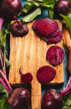 Mavi bir arka plan üzerinde bir vintage ahşap kesme tahtası üzerinde yeşil yaprakları ile taze organik kırmızı pancar. Üstten görünüm, kopya alanı.