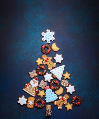 Mavi arka plan üzerinde bir Noel ağacı şeklinde çeşitli Noel kurabiyeleri. Üstten Görünüm.