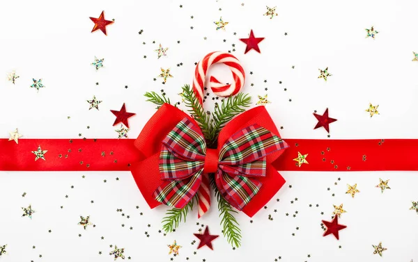 白い背景の上の弓とキャンディ コーンとクリスマスの赤いリボン 平面図です ギフト用の箱のクリスマスの装飾 — ストック写真