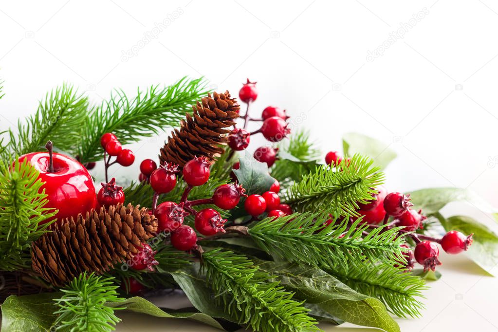 Christmas decoration with fir tree, pine cones, red apples and holly berries