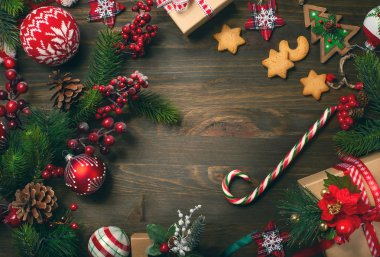 Çerçeve çam dalları, kurabiye ve koyu ahşap arka plan üzerinde Noel süslemeleri ile. Üstten görünüm.