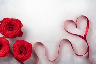 Kırmızı gül ve kırmızı kurdele vintage beyaz-gri arka plan üzerinde kalp şeklinde. Sevgililer günü için festival kavram. Kopya alanı ile üstten görünüm.