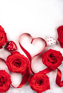 Kırmızı gül ve kırmızı kurdele vintage beyaz-gri arka plan üzerinde kalp şeklinde. Sevgililer günü için festival kavram. Kopya alanı ile üstten görünüm.