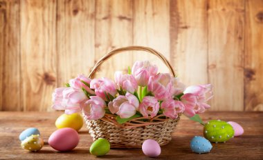 Paskalya Tatil sepet pembe laleler ve rustik tarzı ahşap arka plan üzerinde Paskalya yumurtaları.