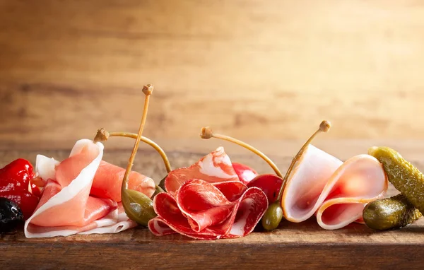 Ассорти из нарезанного хамона, салями, ветчины с оливками, каперсы, огурцы — стоковое фото