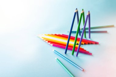 Açık mavi arka plan üzerine ayarlanmış renkli kalemler 