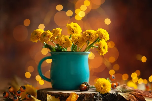 美丽的黄花在蓝色杯在木桌上的散景巴 — 图库照片