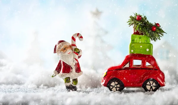 Санта-Клаус и красная игрушечная машина с рождественскими подарками на снегу — стоковое фото