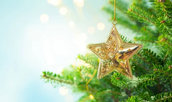 Świąteczne gałęzie jodły z dekoracją złotej gwiazdy na rozmycie — Zdjęcie stockowe