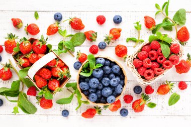 Beyaz ahşap arka planda sepetin içinde çeşitli taze böğürtlenler. Yaz yemeği kavramı. Düz yat, boşluğu kopyala.