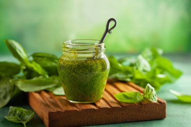 Ev yapımı pesto sosu taze fesleğen, parmesan peyniri ve tahta tahtada kaşıkla cam kavanozda çam fıstığı. Ön görünüm, boşluğu kopyala