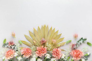 Beyaz ve mercan çiçekleri, kurutulmuş palmiye yaprakları ve pastel gri arka planda gümüş yeşili yapraklar. Fotokopi alanı olan çiçek bileşimi, düz konum.