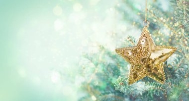 Bulanık mavi arka planda altın yıldız süslemeli Noel ağacı dalları. Noel ve Kış kavramı.