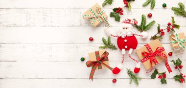 Noel arkaplanı hediye kutuları, Noel Baba oyuncağı ve beyaz ahşap arka planda Holly ve köknar dalları. Kış festivali konsepti. Düz yat, boşluğu kopyala.