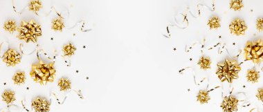 Beyaz arka planda altın parıltılı kurdele süslemeleri olan Noel veya Yeni Yıl kompozisyonu. Düz yat ve boşluğu kopyala.