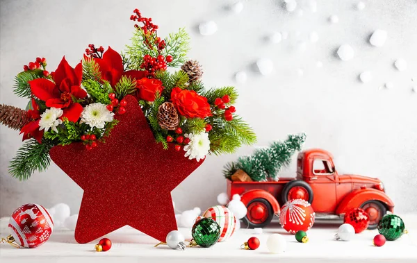 过冬的花朵摆设成红星形的花瓶 桌上摆放着圣诞彩灯 假日圣诞花卉的构图 — 图库照片