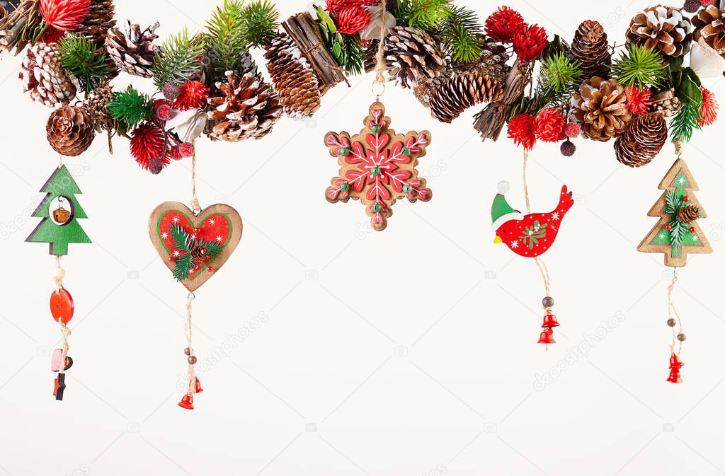 Christmas or New Year decor with hanging garland of fir branches, red berries, pine cones and other wooden ornaments. Winter festive concept