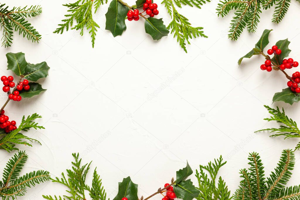 Christmas background with branches of fir tree, evergreens and holly with red berries on white. Winter nature concept. Flat lay, copy space.